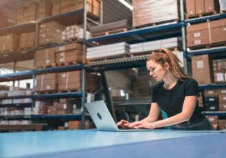 Self Storage Manager Working On Laptop In Wearhouse